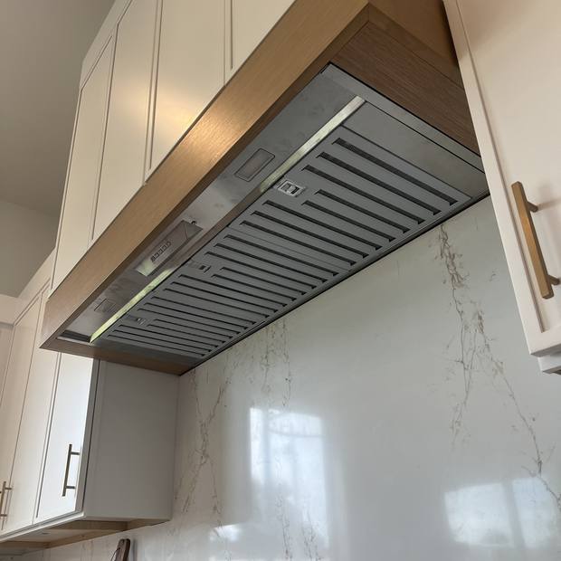 White oak and painted kitchen hood above a range